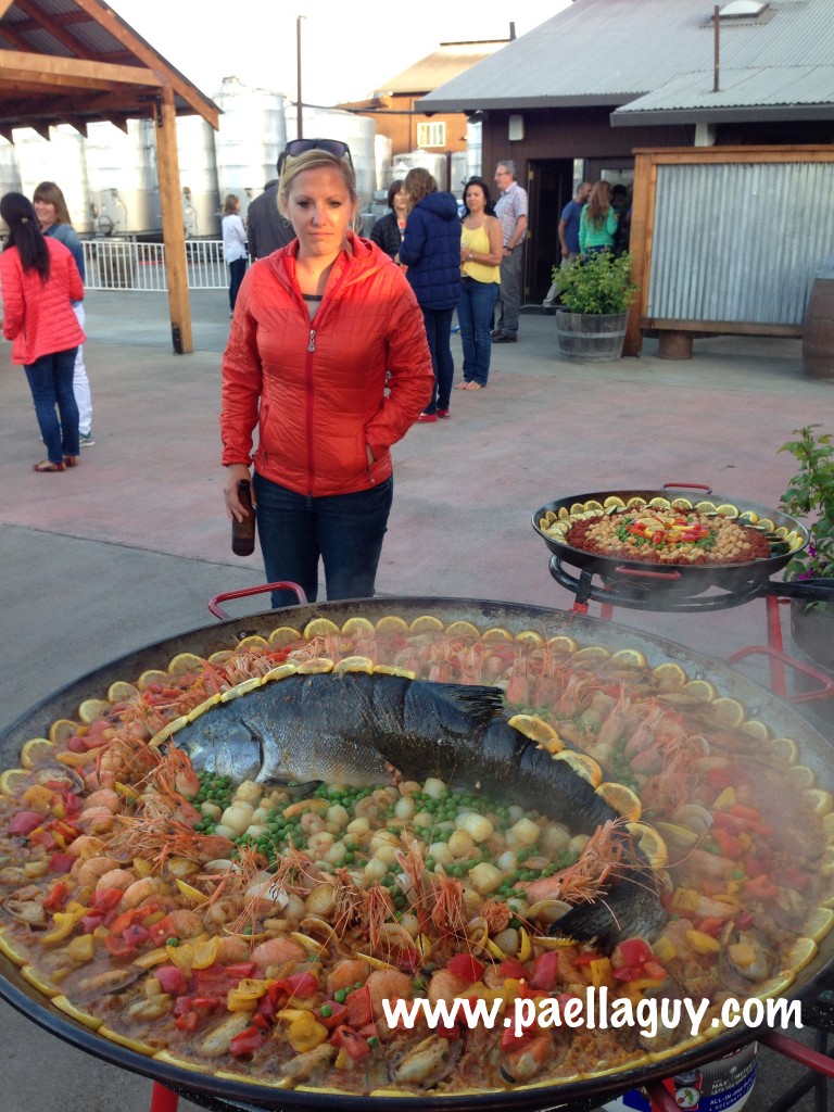 A guest with Camelbak admires Salmon Paella created by Paella Guy.